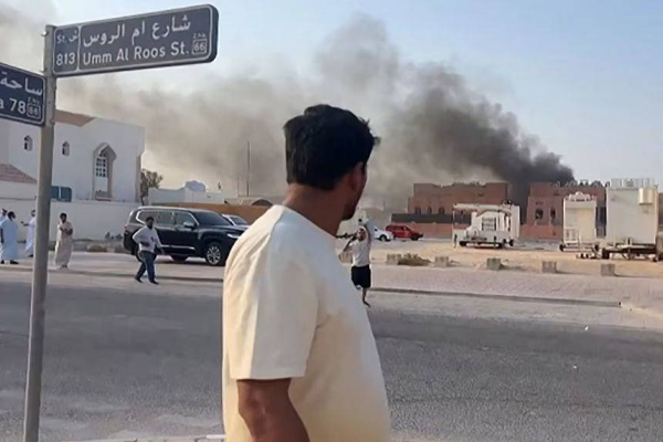 A screengrab from TV footage shows a man looking at smoke billowing after explosions in Qatar's capital Doha on September 9, 2025
