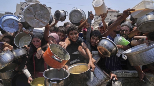 Palestinians hold out pots and pans at a community kitchen in Gaza City on Saturday, July 26, 2025
