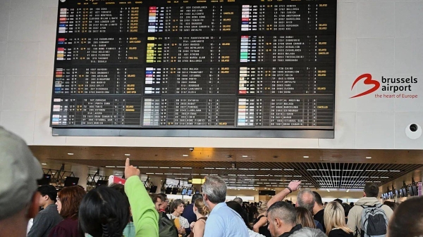An airport employee points at a departure board after a cyber attack caused delays at Brussels International Airport in Zaventem, Belgium, Saturday, Sept. 20, 2025