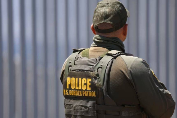 A US Customs and Border Protection Border Patrol agent stands in front of the US-Mexico border wall in Imperial Beach, California, on August 17