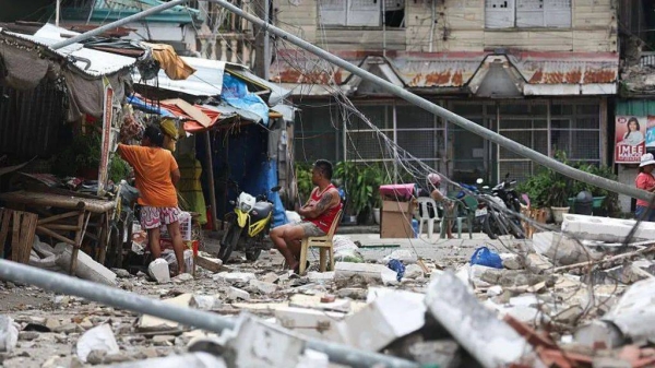 Residents of Bogo City, Cebu province, stay on the streets near the debris of damaged buildings amid frequent aftershocks, following a magnitude 6.9 earthquake